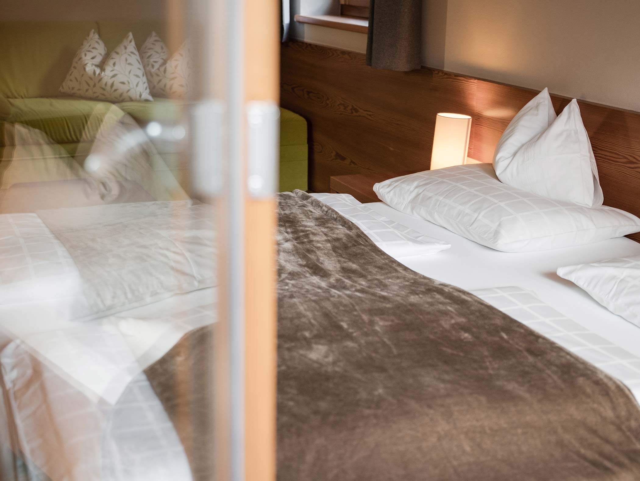 Ein ordentlich gemachtes Bett mit weißen Kissen, einer braunen Decke und einer Nachttischlampe in einem gemütlichen Schlafzimmer. - Hotel Moosmair