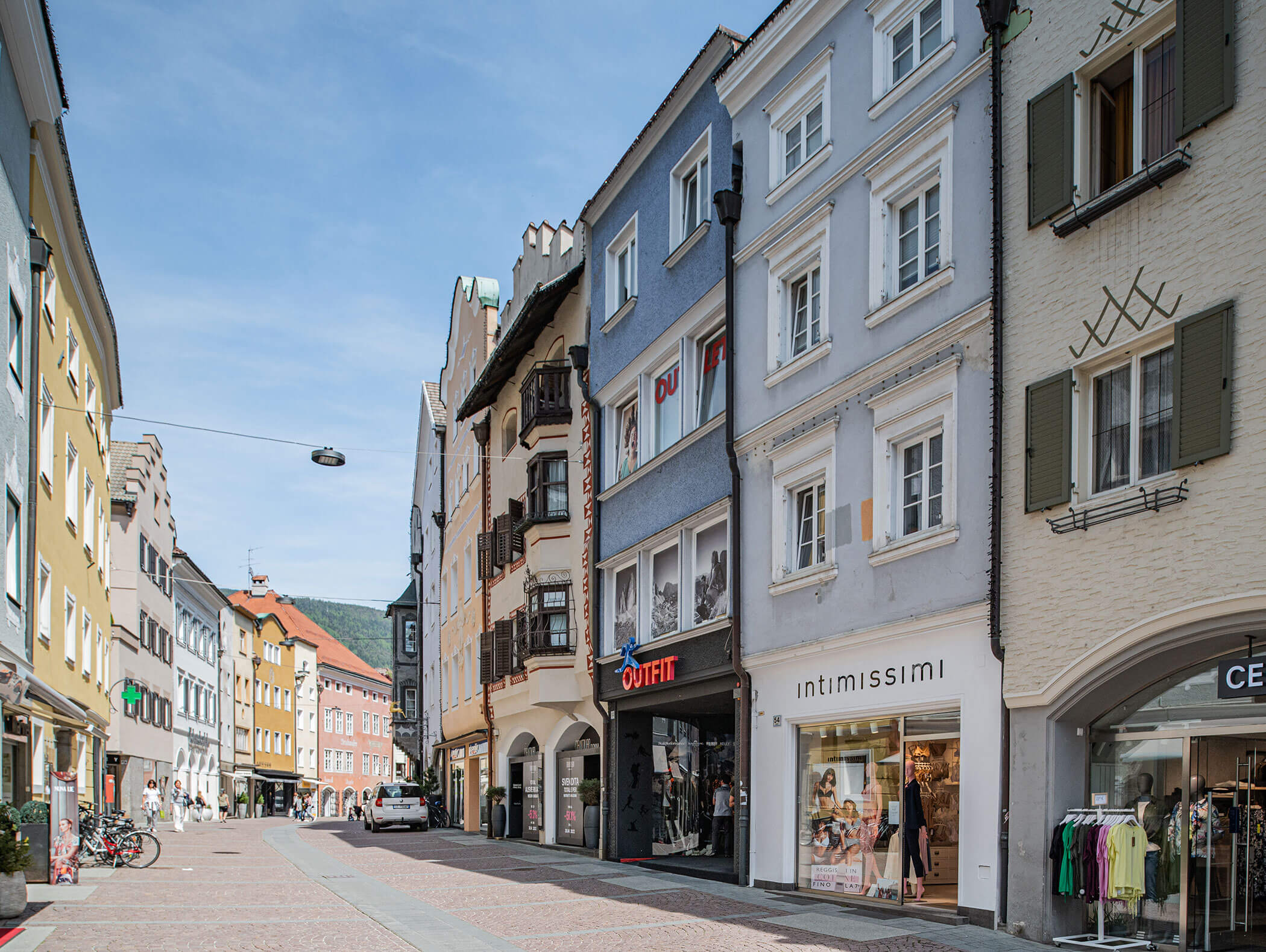 Fußgängerzone mit bunten Geschäften und Wohnungen an einem sonnigen Tag in einer europäischen Stadt. - Hotel Moosmair