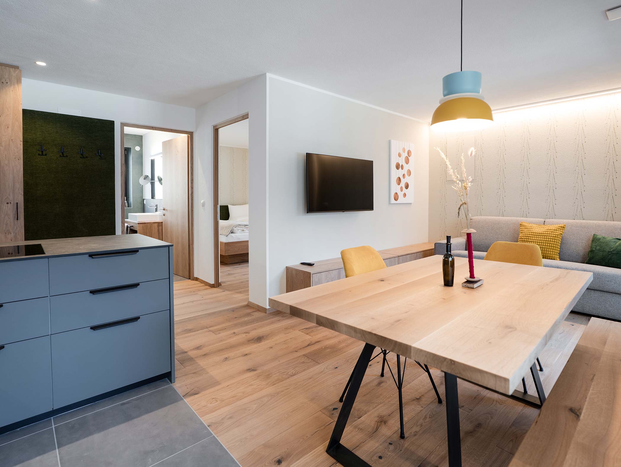 Moderner offener Wohnbereich mit Küche, Esstisch und gemütlicher Sitzecke mit Sofa und TV. - Hotel Moosmair