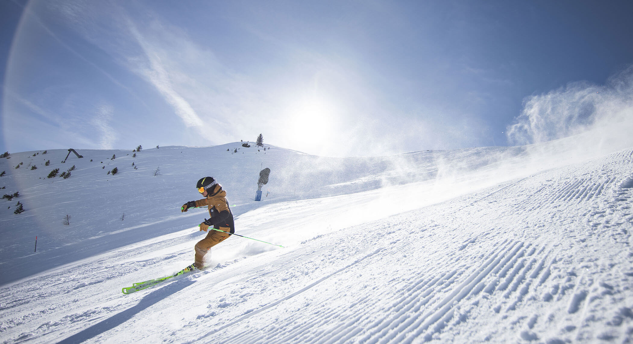 Ein Skifahrer fährt bei strahlend blauem Himmel und strahlender Sonne einen verschneiten Berghang hinunter. - Hotel Moosmair